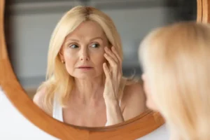 middle aged woman checking her face in the mirror