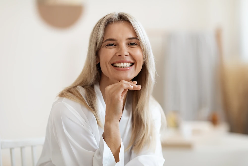 Smiling blonde woman posing at white bathroom at home