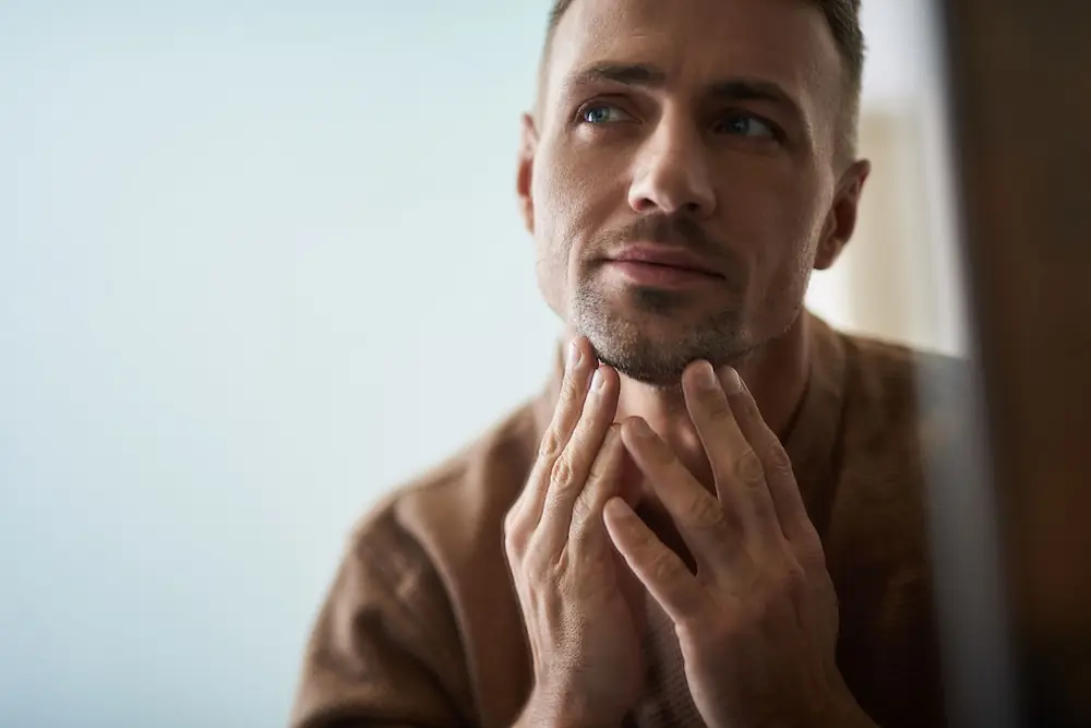 man looking in the mirror at his face